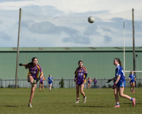 Kilmacud number 8 kicking the ball high over two other players