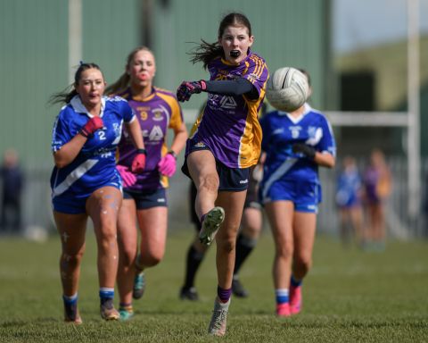 Kilmacud number 20 being chased by two opponents as she kicks the ball